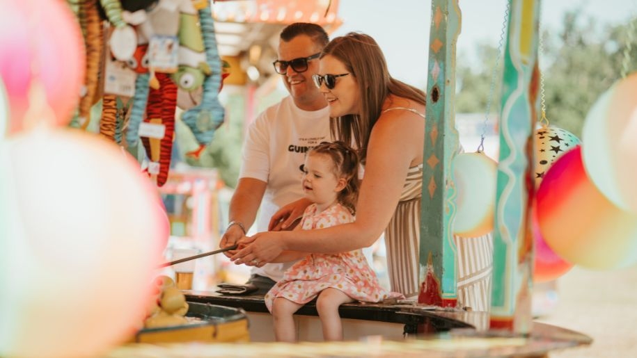 Father, mother and young child at a fete stall.