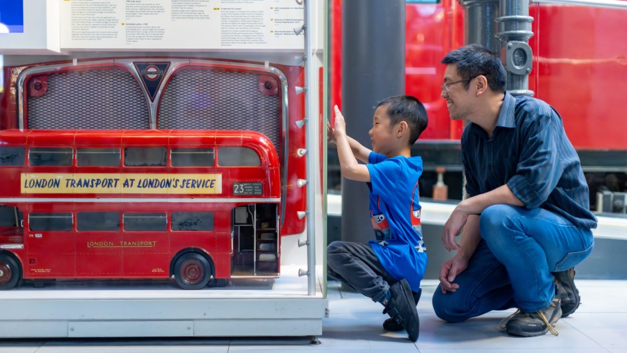 Father and son looking at model London bus at London Transport Museum.