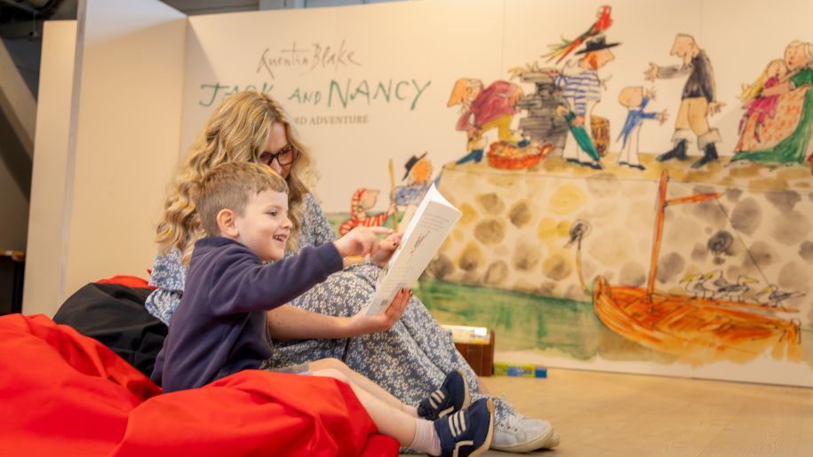 boy sits on red beanbag reading story