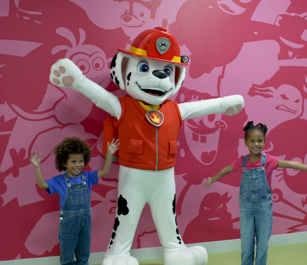 two children stand with paw patrol character
