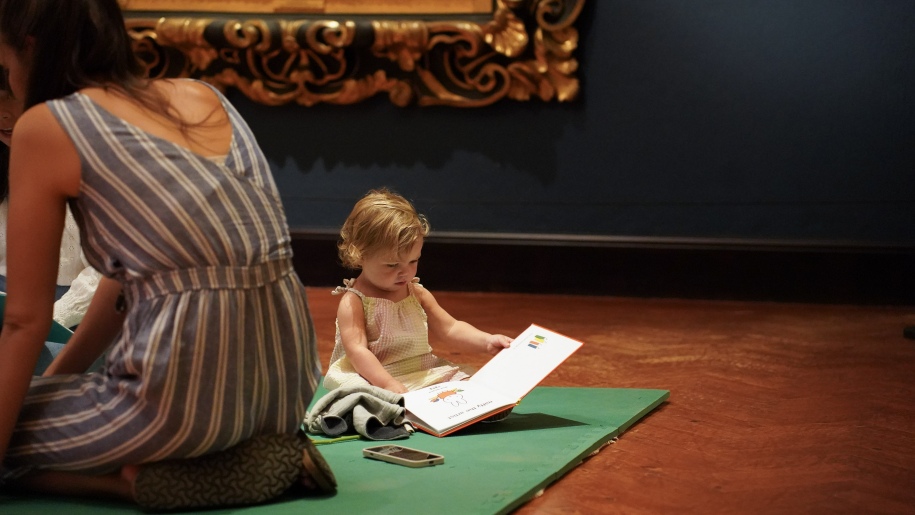 Young child sitting on the floor looking at a book.