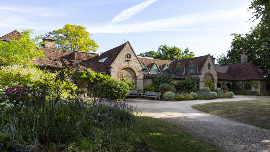 Large stone building surrounded by shrubs in summer.