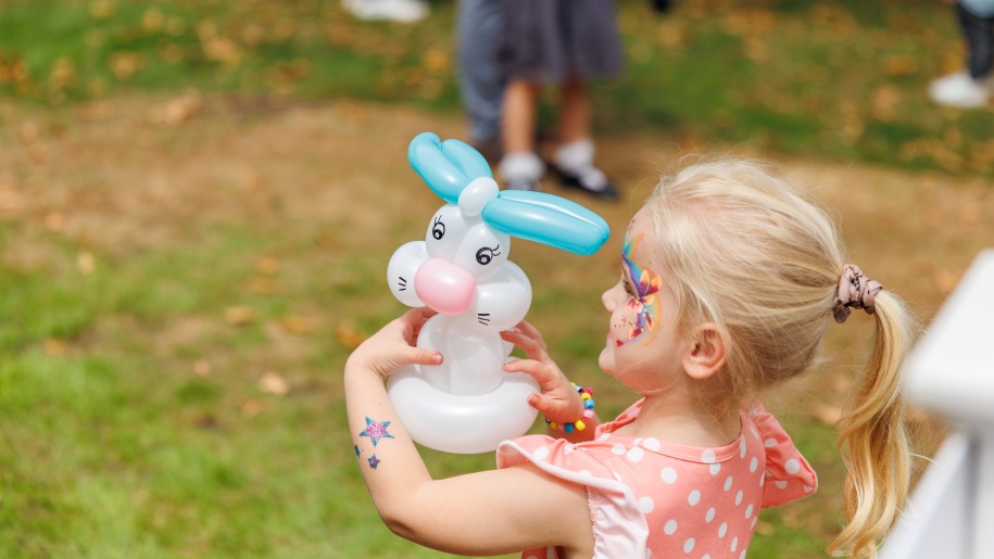 Girl holding a balloon model of a rabbit.