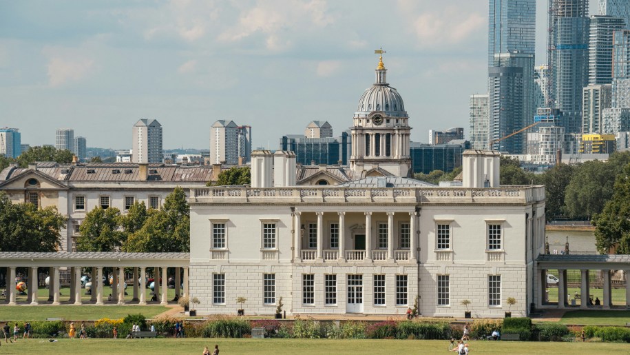Large white house in the classical style with modern tower blocks behind.
