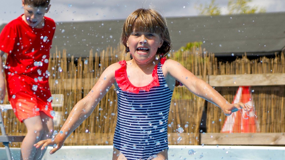 Girl in a blue and red swimming costume splashing in water.