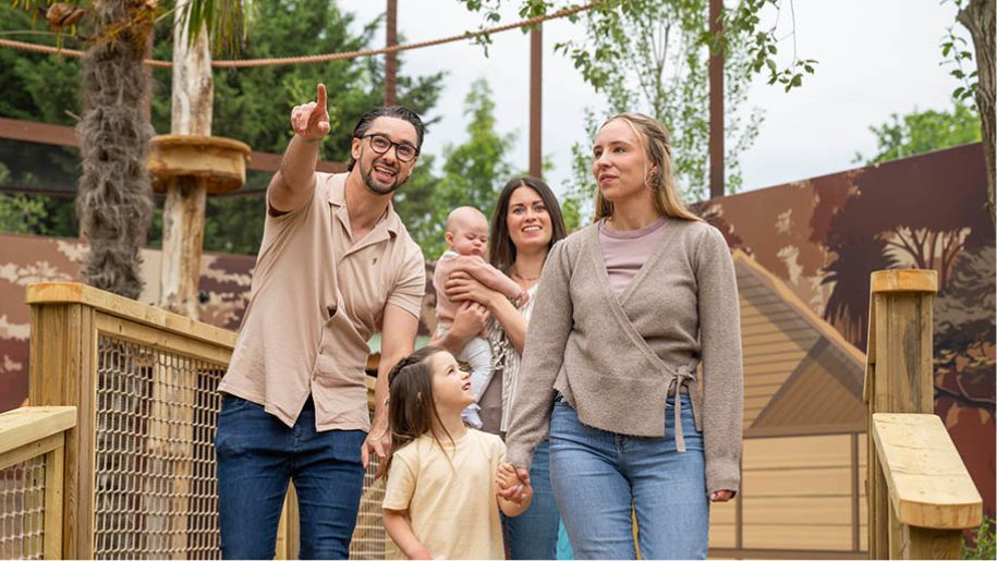 young family walk around wooden structure at zoo