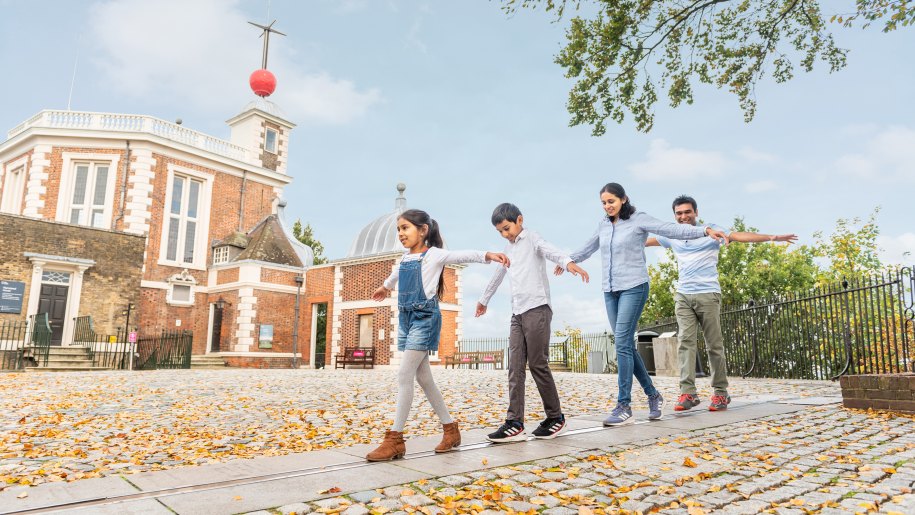 Family walking along the meridian line at the Royal Observatory in Greenwich.