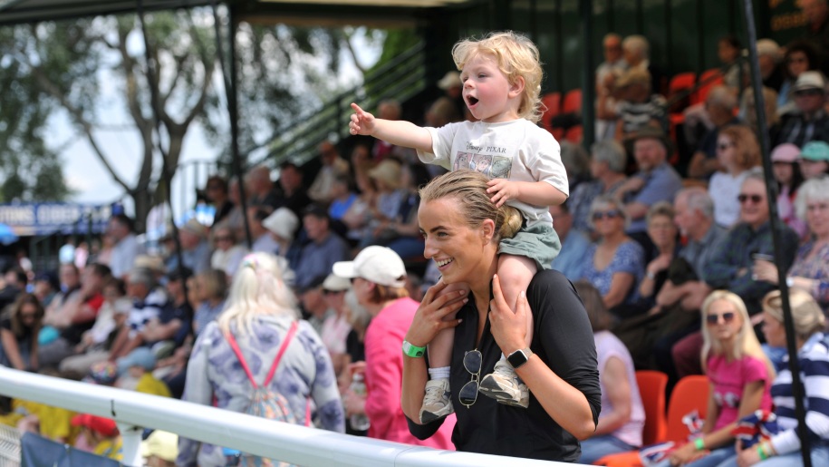 Child sitting on a woman's shoulders watching arena entertainment at a show.