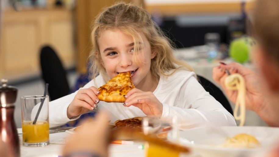 Girl eating a slice of pizza.