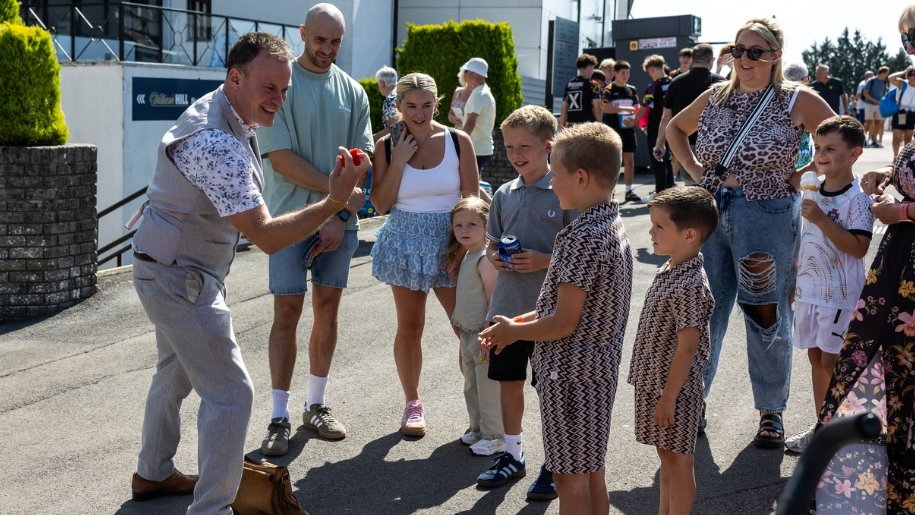 Families watching a children's entertainer perform a trick.
