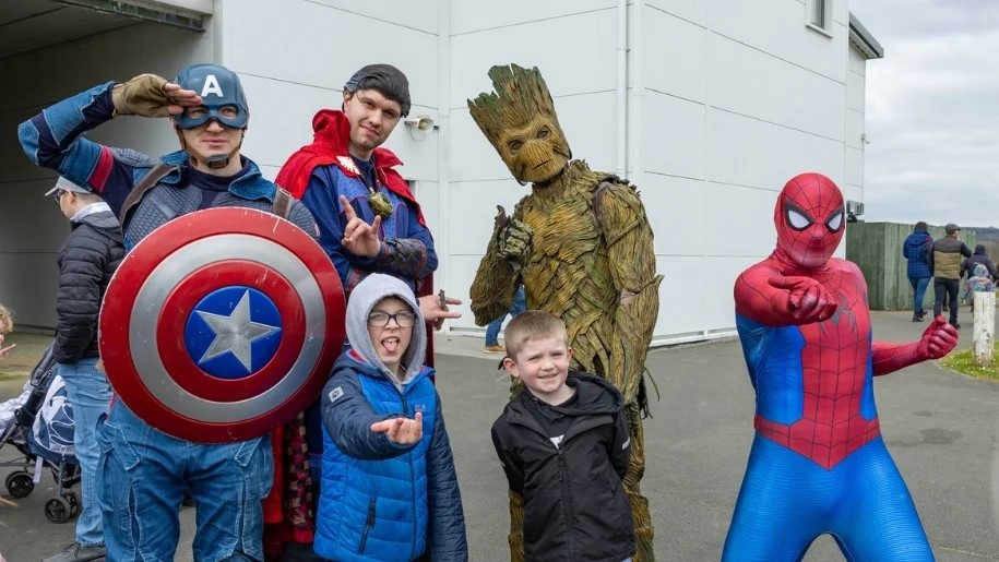 Film and TV characters including Spiderman posing with two children.