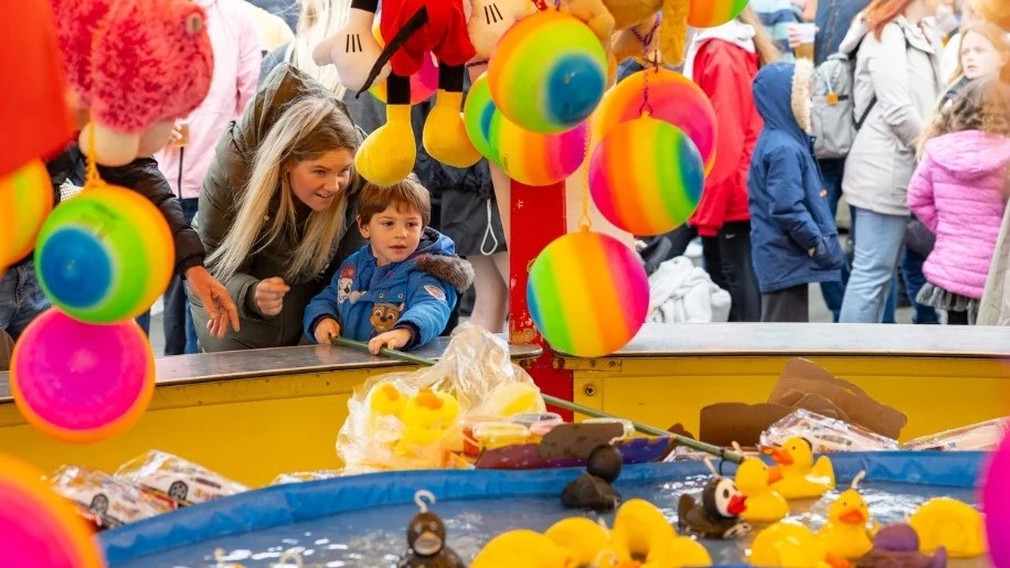 Mother and child trying hook-a-duck at a funfair.