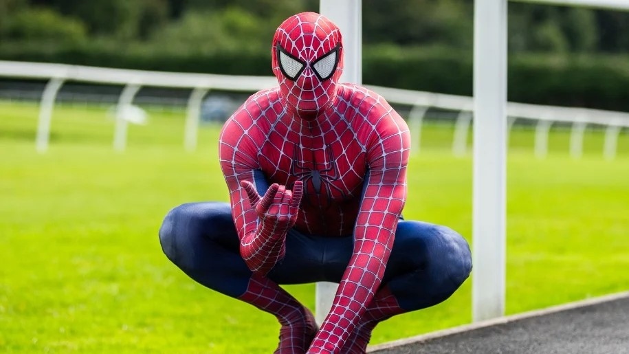 Spiderman crouching beside a race track.