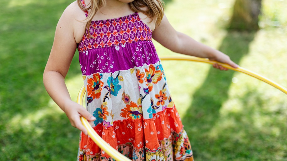 Girl in a summer dress hula hooping.