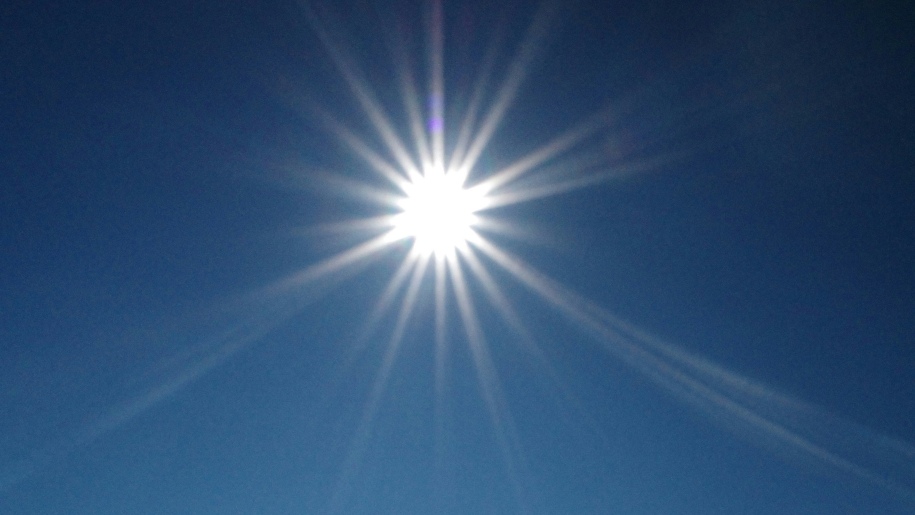 The bright Sun shining in a cloudless blue sky.
