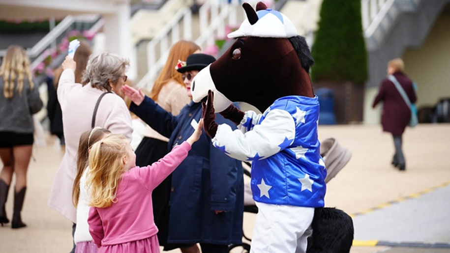 Two girls giving a high five to the horse mascot at Ascot Racecourse.