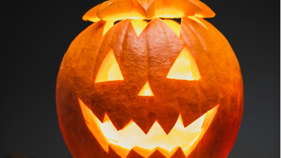 Single large orange pumpkin glowing in the dark for Halloween.