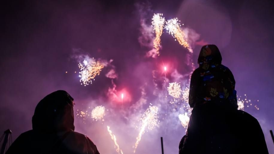 Silhouettes of a family watching an after-dark fireworks display.