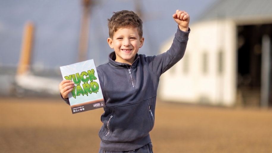Child holding a booklet titled Yuck Yard.