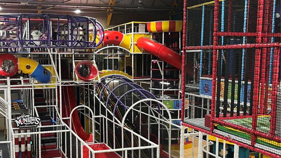 Indoor play centre with tube and wavy slides plus other obstacles.