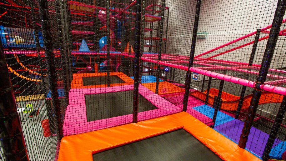 Series of trampolines surrounded by black netting.
