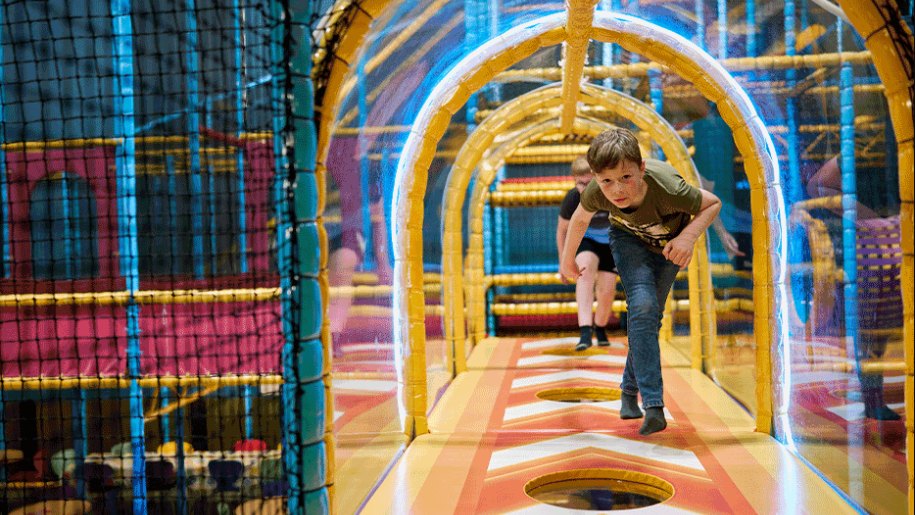 Children running through a tunnel in a soft play centre.