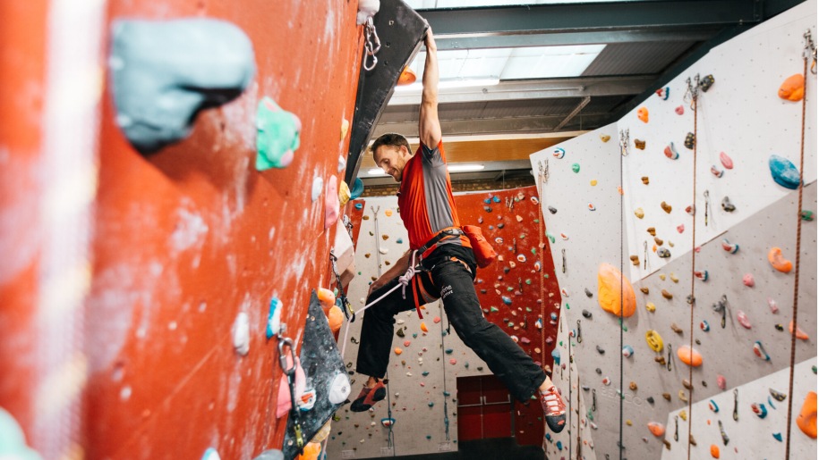 Man swinging on an indoor climbing wall.