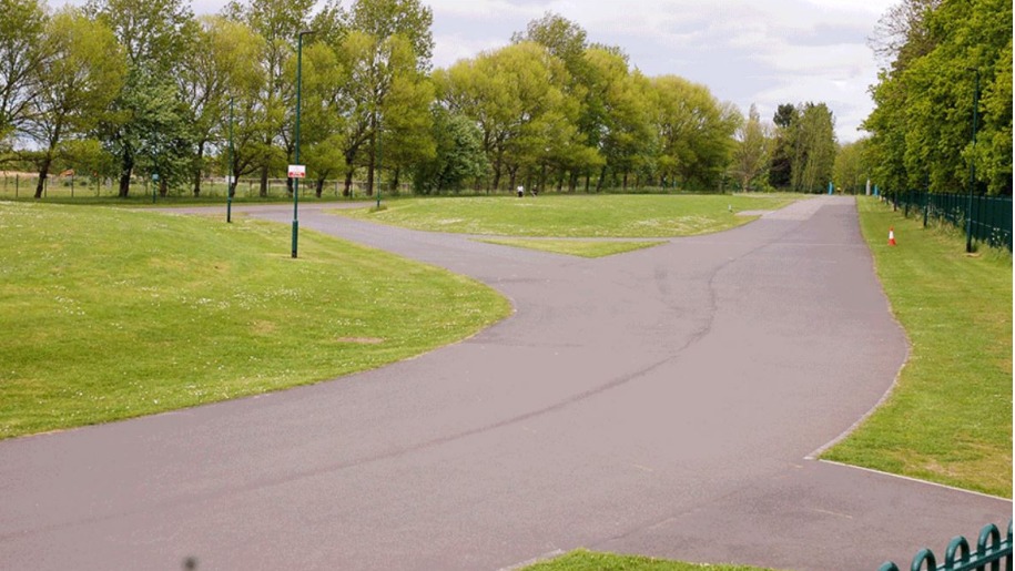 Flat tarmac paths through green open space.