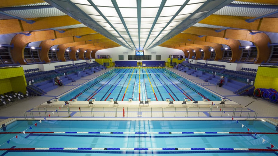 Two indoor swimming pools marked with lanes and with spectator areas alongside..