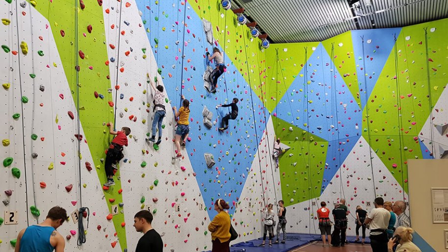 Young people on a colourful indoor climbing wall.