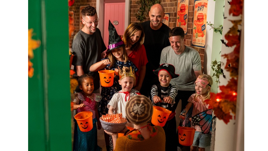Children in fancy dress holding out orange buckets while trick or treating at Halloween.