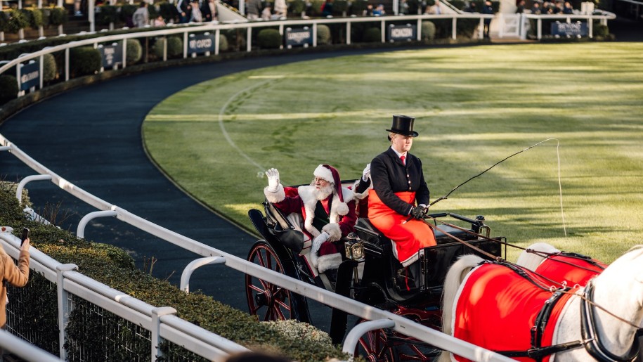 Father Christmas in a horse-drawn carriage waving at crowds at Ascot.