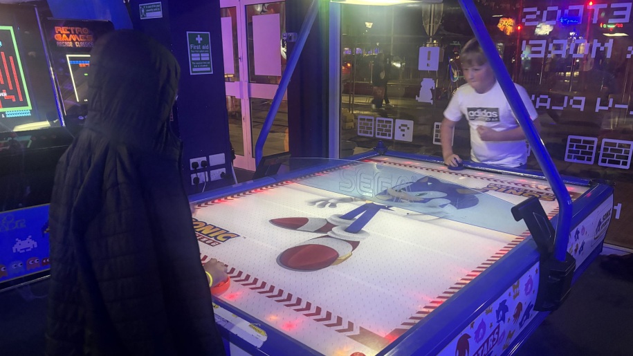 Boys playing on a game at an indoor arcade.