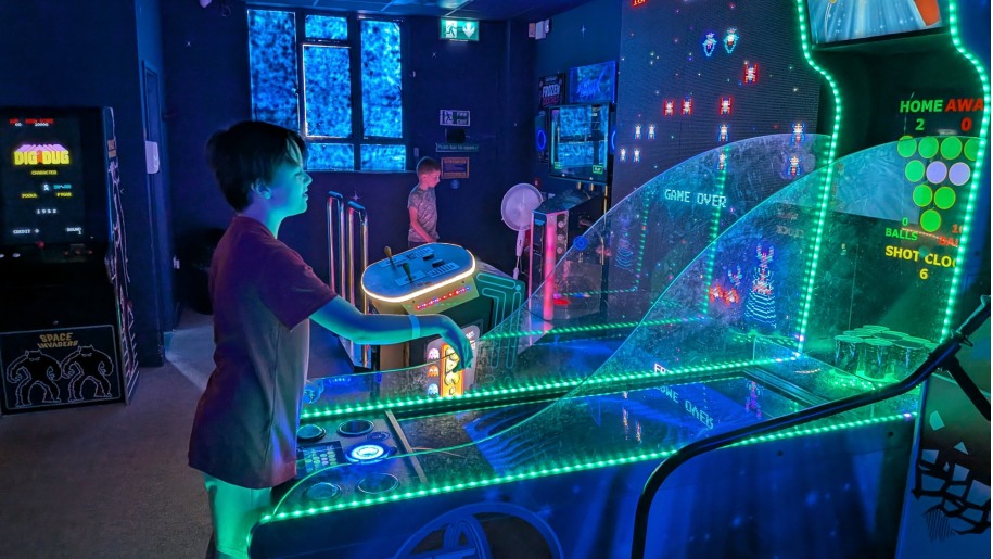 Boy playing on a game in an indoor arcade.