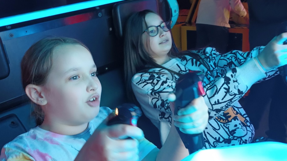 Two girls holding controllers while playing a game at an arcade.