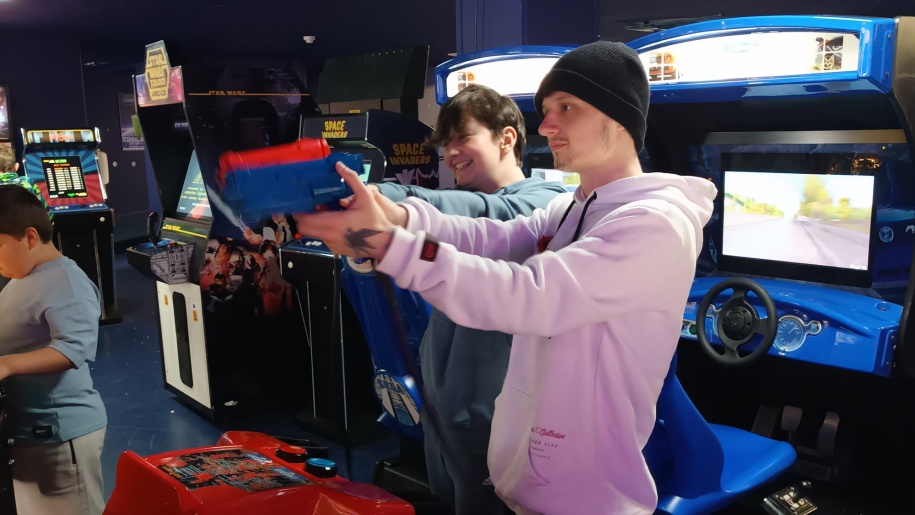 Young people playing a shooting game at an arcade.