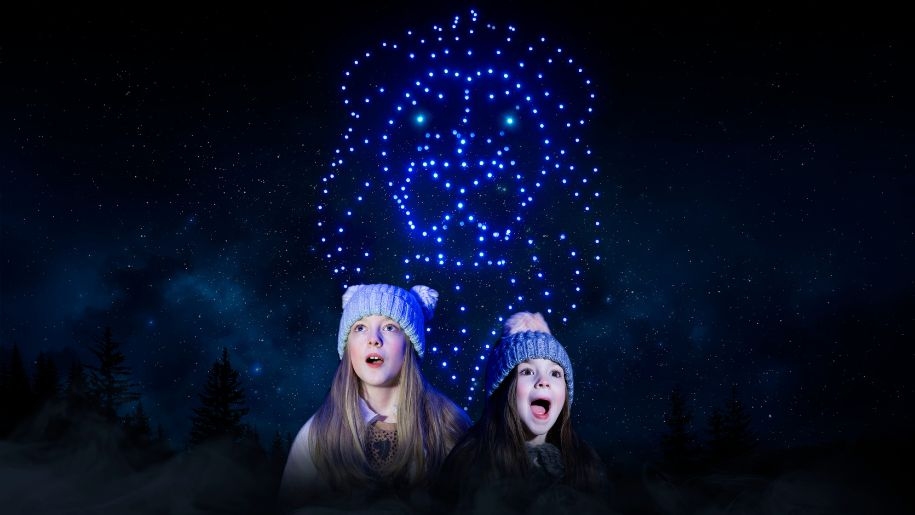 Two children watching a drone show in the night sky.
