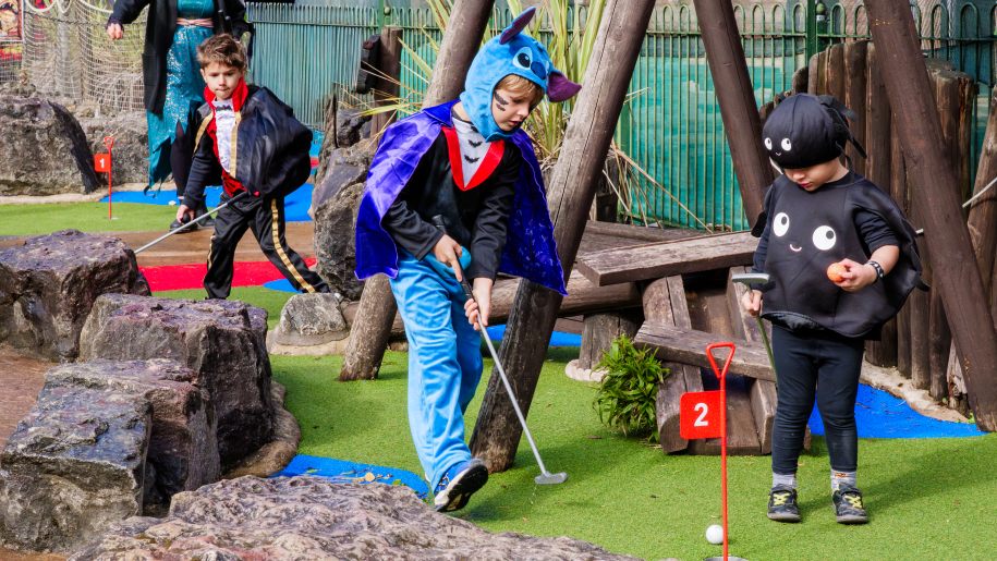Children in Halloween fancy dress playing crazy golf.