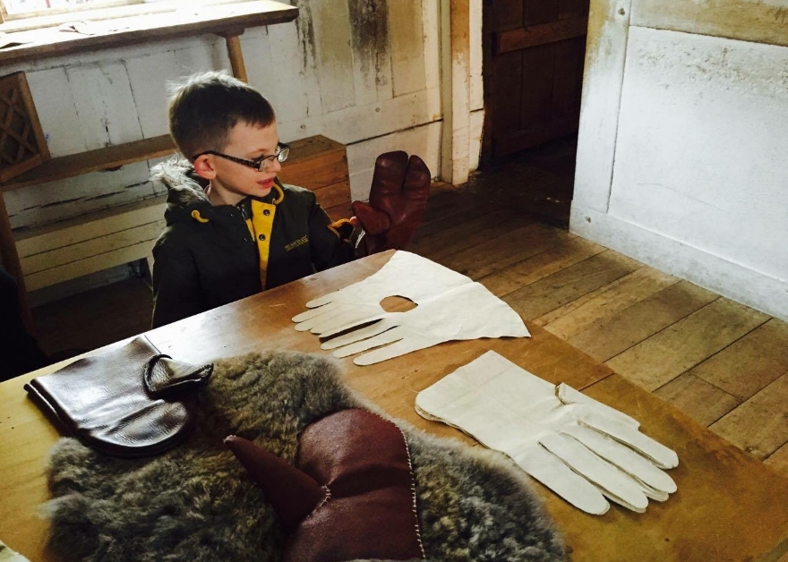 A child looking at gloves and other clothing at one of Shakespeare's Family Homes in Warwickshire.